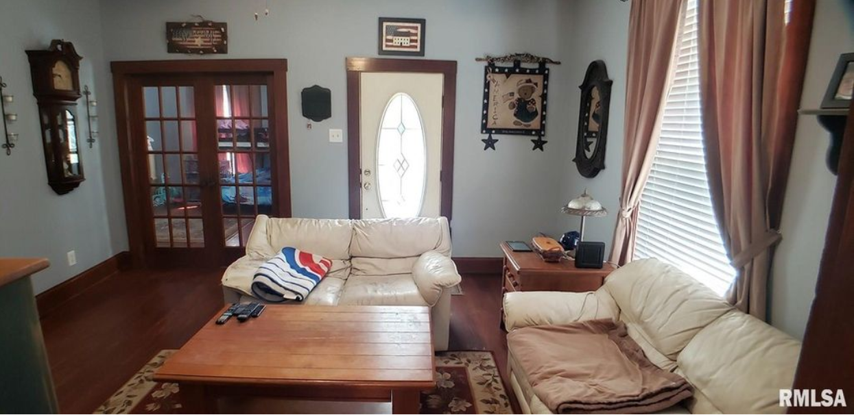 A living room with a couch , chair , coffee table and clocks.