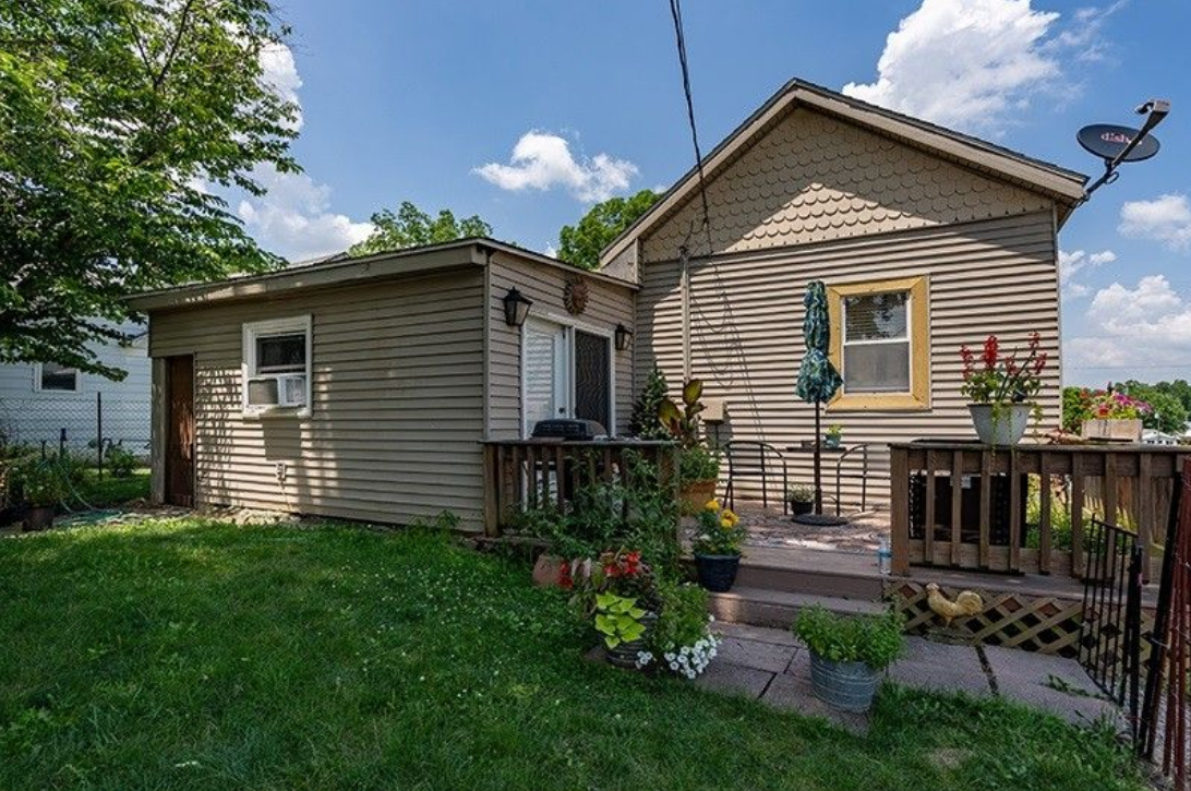 A small house with a deck and flowers in front of it.