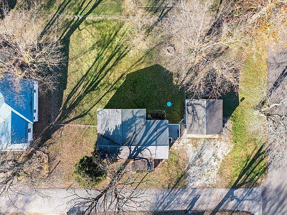 An aerial view of a house and yard with trees and grass.