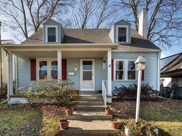 A small blue house with red shutters and a porch.