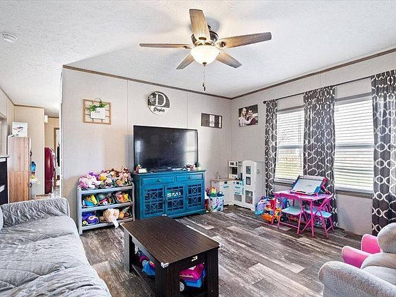 A living room with a ceiling fan and a flat screen tv.