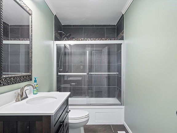 A bathroom with a toilet , sink , mirror and shower.