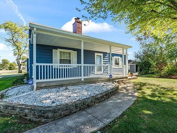 A blue house with a white porch and a walkway leading to it.