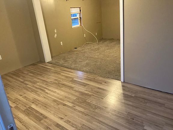 A room with hardwood floors and a window in a mobile home.