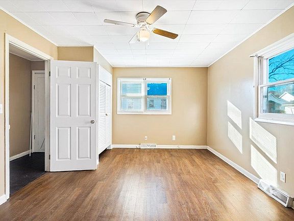 An empty room with hardwood floors and a ceiling fan.