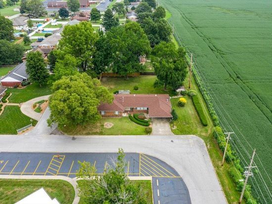 An aerial view of a house surrounded by trees and a parking lot.
