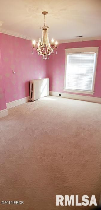 An empty room with pink walls and a chandelier hanging from the ceiling.