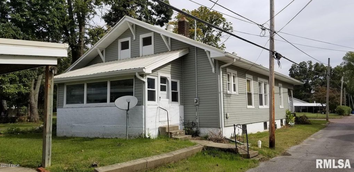 A white house with a satellite dish on the side of it is for sale.