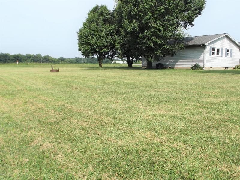 A house sits in the middle of a lush green field