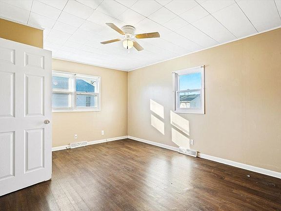 An empty bedroom with hardwood floors and a ceiling fan.