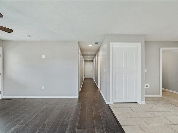 A long hallway in a house with hardwood floors and a ceiling fan.