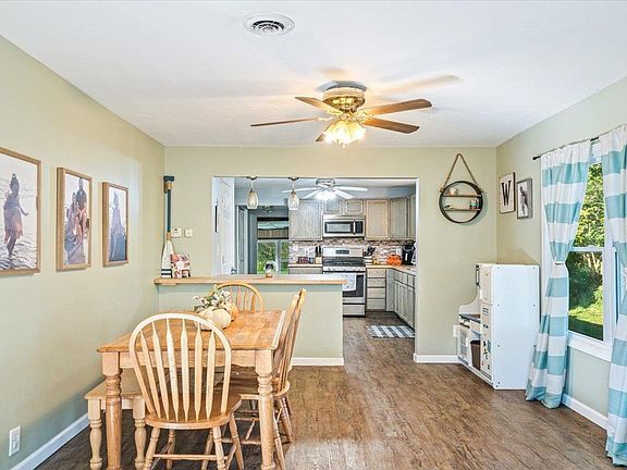 A dining room with a wooden table and chairs and a ceiling fan.