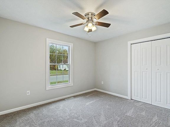 An empty bedroom with a ceiling fan and a window.