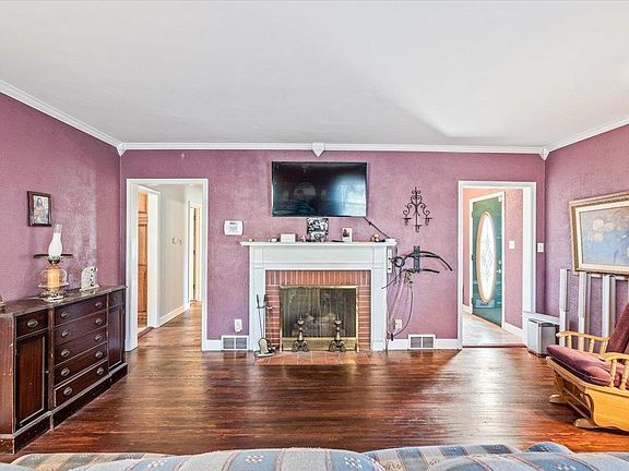 A living room with purple walls and a fireplace.