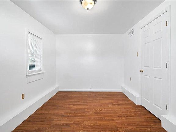 An empty room with hardwood floors and white walls.