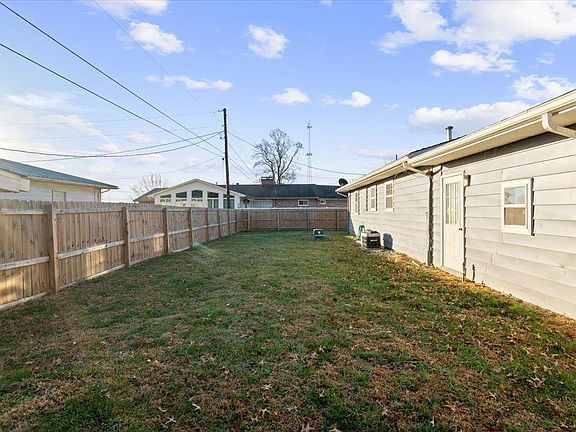 A backyard with a fence and a house in the background.