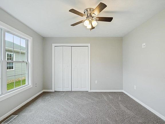 An empty bedroom with a ceiling fan and a window.