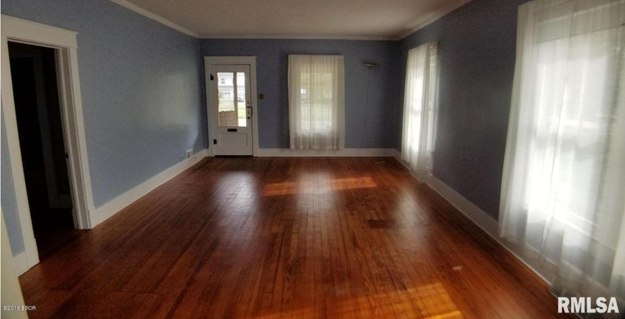 An empty living room with hardwood floors and blue walls.
