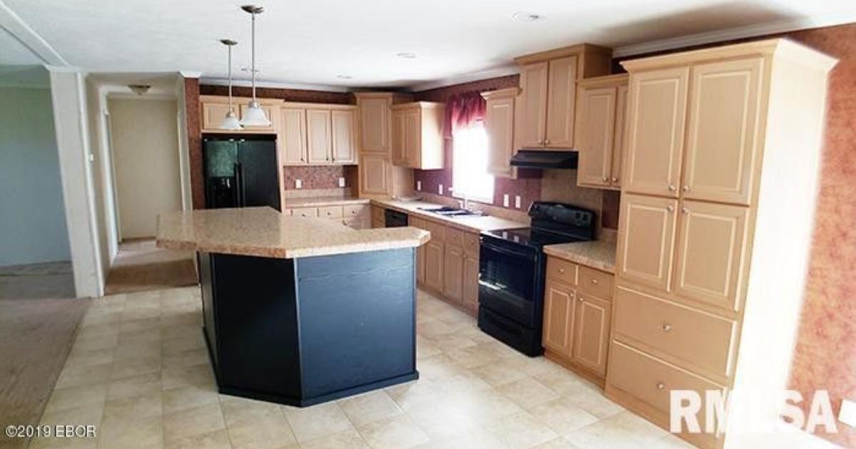 A kitchen in a mobile home with a large island in the middle.