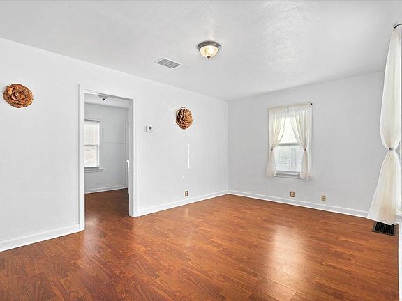 An empty living room with hardwood floors and white walls.