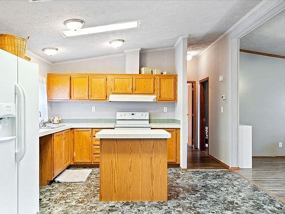A kitchen in a mobile home with wooden cabinets and a white refrigerator.