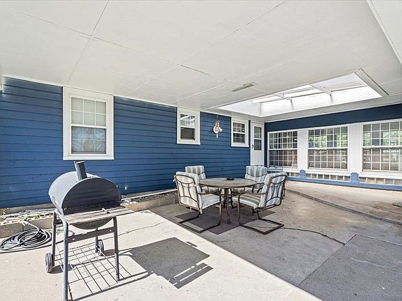 A blue house with a patio with a table and chairs and a grill.