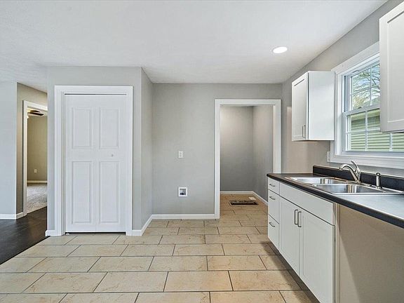 A kitchen with a sink , cabinets , and a window.