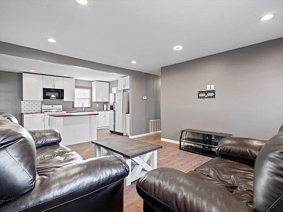 A living room with a couch , chair , coffee table and kitchen.