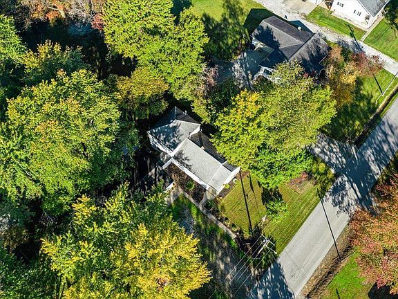 An aerial view of a house in a residential area surrounded by trees.