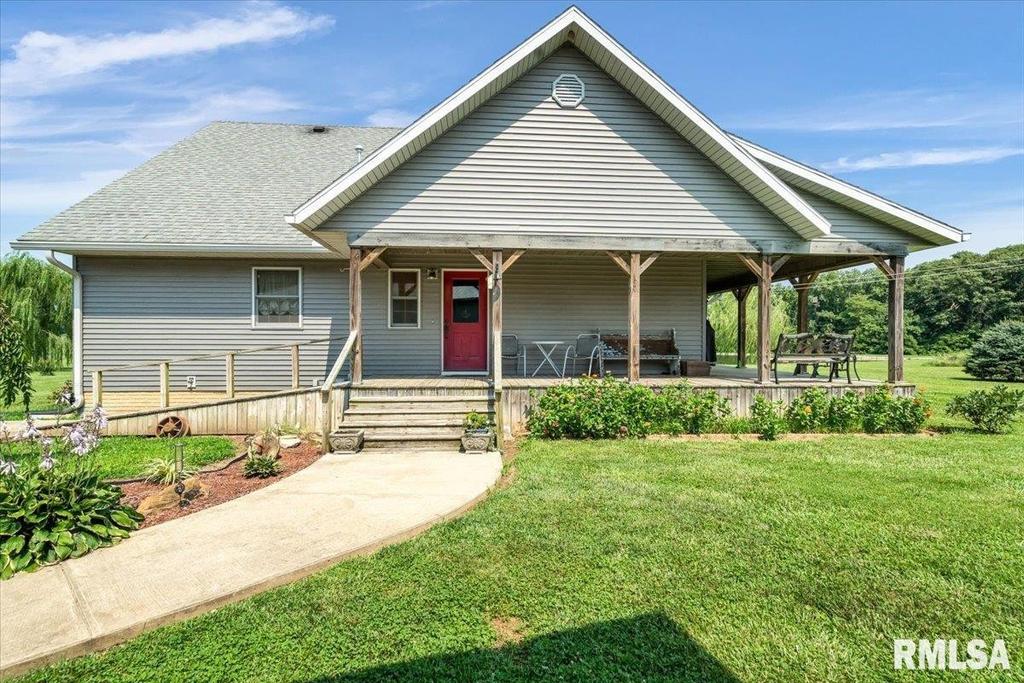 A house with a porch and a red door is for sale.