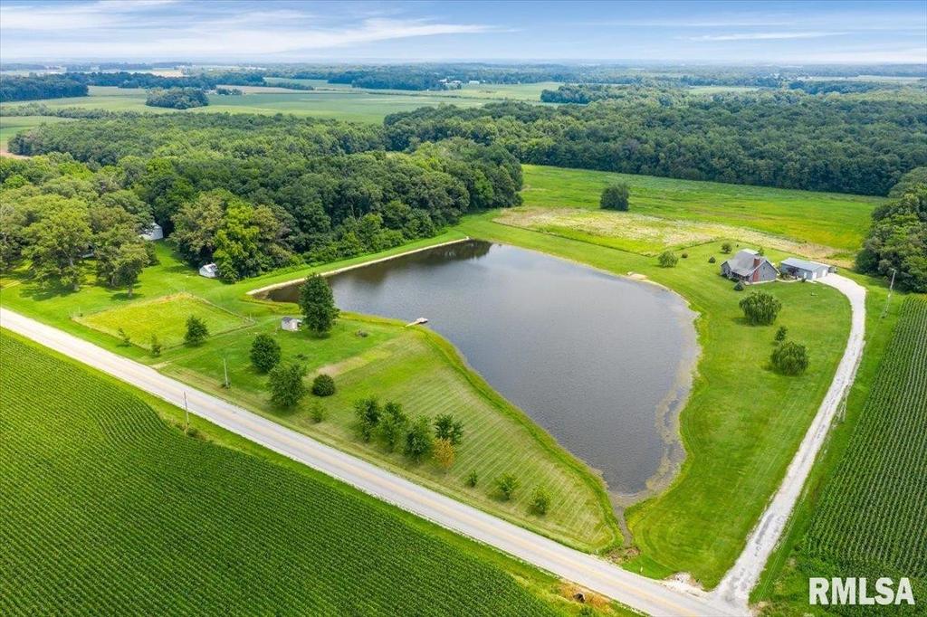An aerial view of a farm with a pond and a road.