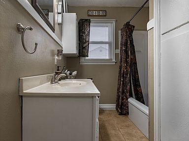 A bathroom with a sink , shower , and window.