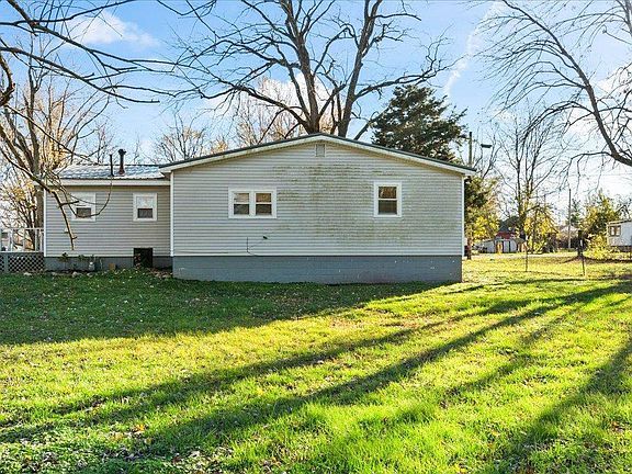 A mobile home is sitting in the middle of a lush green field.