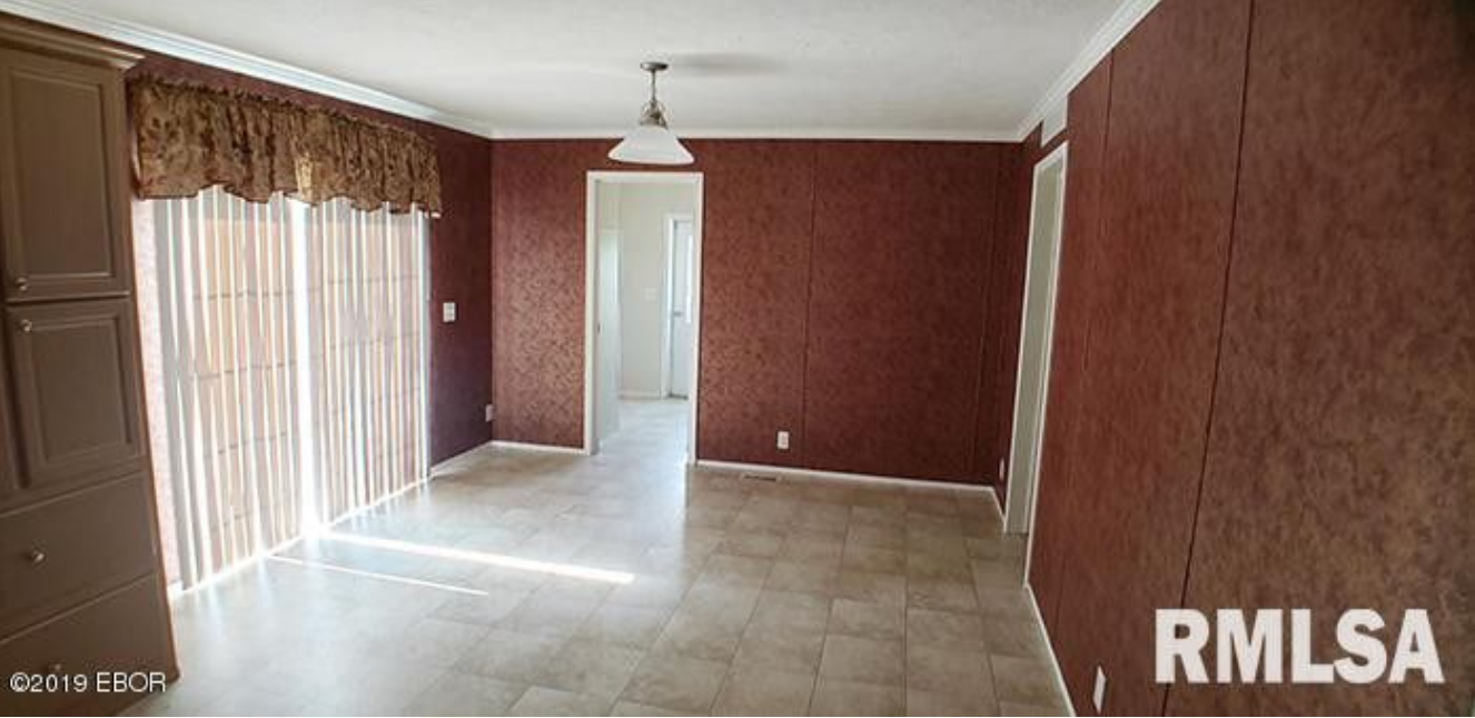 An empty living room with a sliding glass door and a ceiling light.