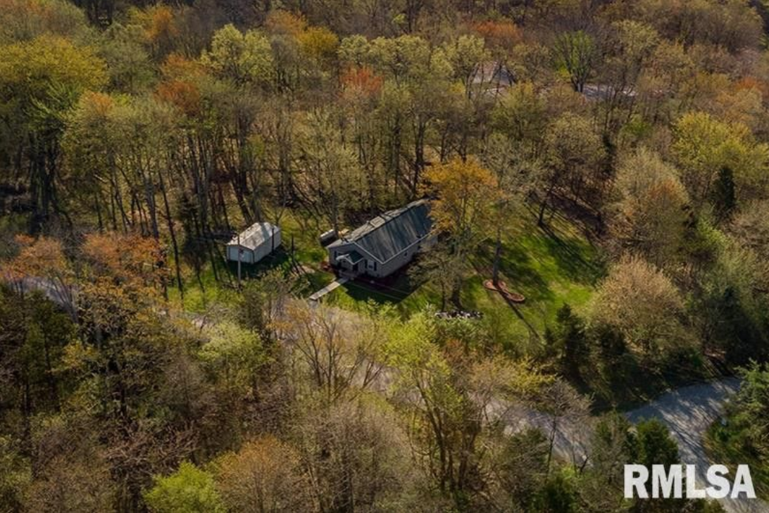 An aerial view of a house in the middle of a forest.