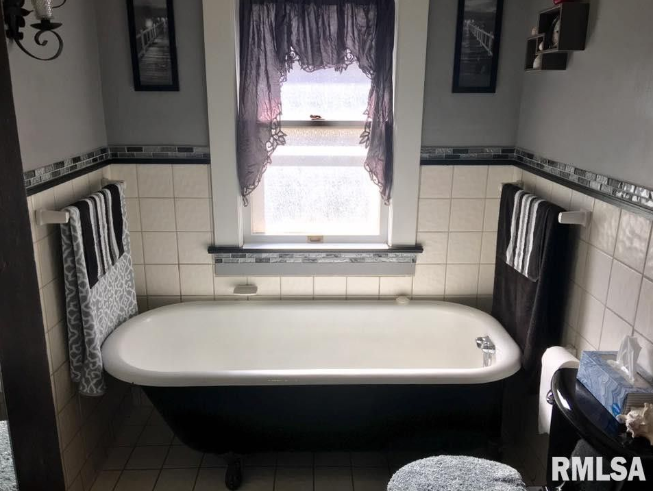 A bathroom with a tub and a window with rmlsa written on the wall