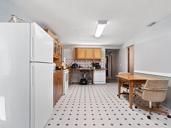 A kitchen with a table and chairs and a refrigerator.