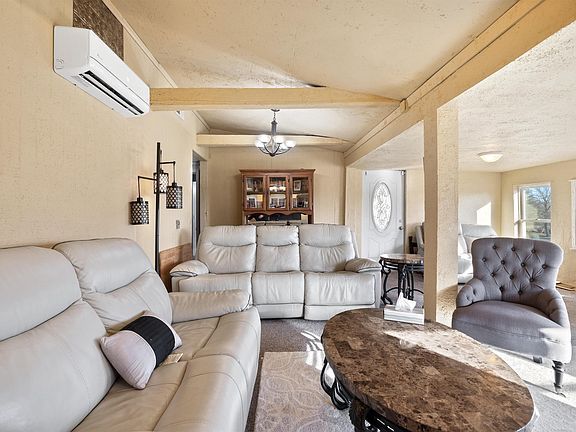 A living room with a couch , chair , coffee table and air conditioner.