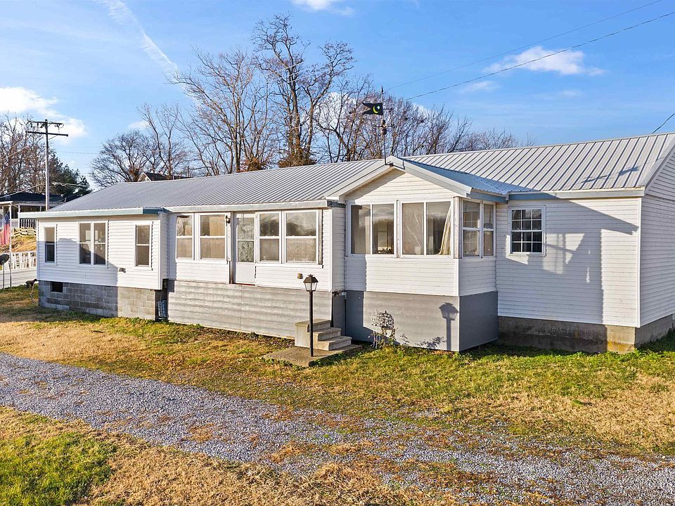 A white house with a porch and a lot of windows is for sale.