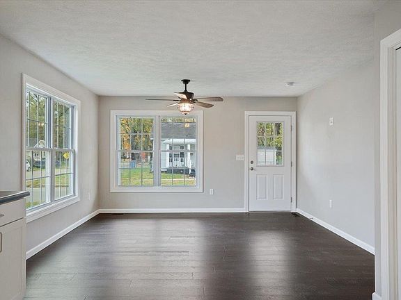An empty living room with hardwood floors and a ceiling fan.