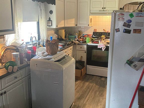 A kitchen with a washing machine , refrigerator , stove and sink.