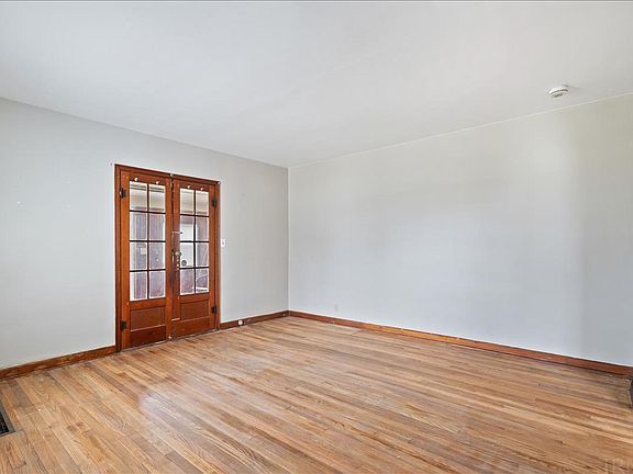An empty living room with hardwood floors and white walls.