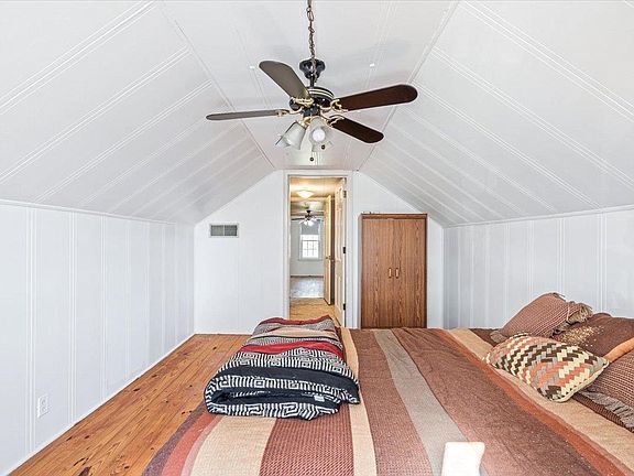 A bedroom with a ceiling fan and a bed.