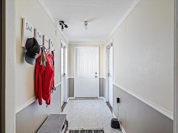 A hallway with clothes hanging on hooks and a bench.