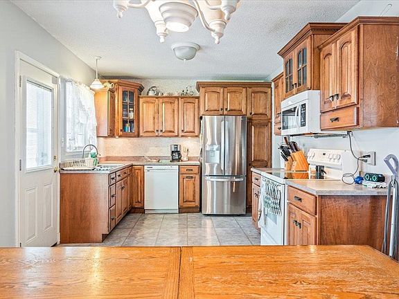 A kitchen with wooden cabinets , stainless steel appliances , and a wooden table.