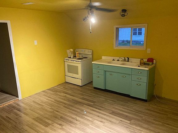 A kitchen with yellow walls , blue cabinets , a stove and a sink.