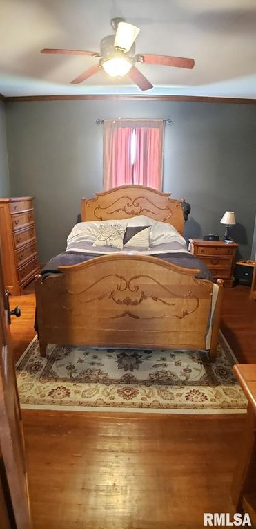 A bedroom with a bed , dresser , nightstand , rug and ceiling fan.