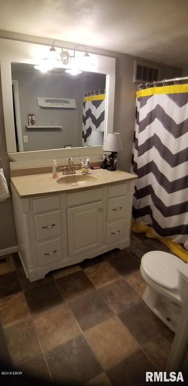 A bathroom with a sink , toilet , mirror and shower curtain.