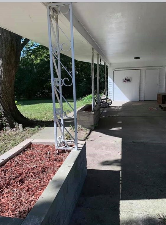 A porch with a white roof and a tree in the background