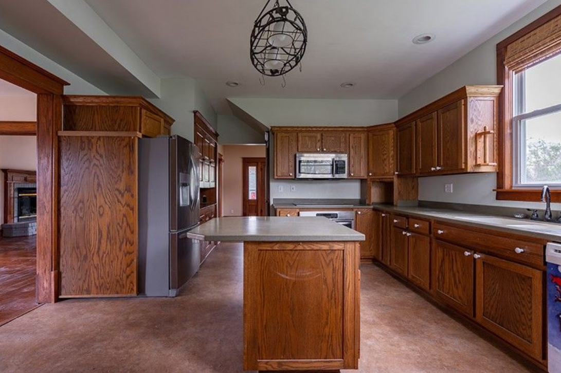 An empty kitchen with wooden cabinets and stainless steel appliances.